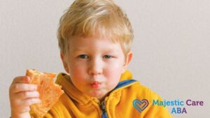 A young boy in a yellow hoodie looks confidently at the camera while holding a piece of toast.