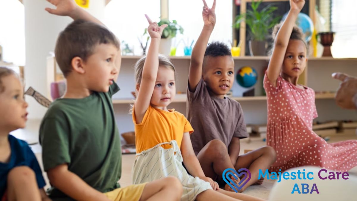 A group of children in a brightly lit classroom, focused and raising their hands to recite.