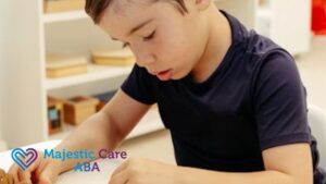 A boy in a black shirt, focused on his artwork, looking down in a quiet room.