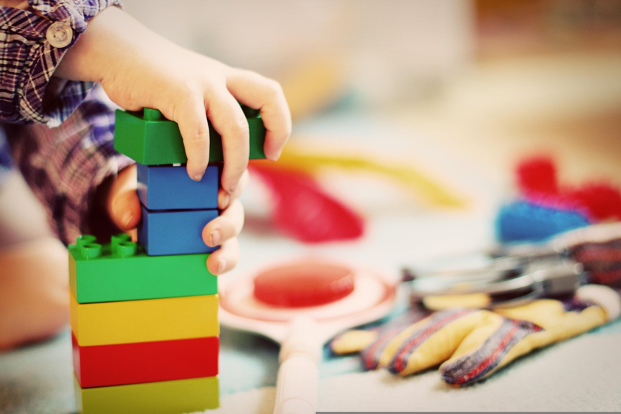Child engaged in ABA therapy, stacking and playing with colorful blocks.