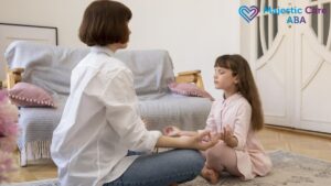 ABA therapy session, a female therapist teaches a young boy breathing techniques as they sit cross-legged on the floor together.