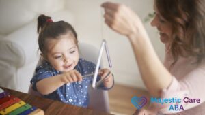ABA therapy session where a therapist holds a musical triangle for an amused young girl, sharing a joyful bonding moment.