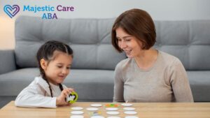 ABA therapy session with a therapist smiling at a young girl’s efforts during a visual picture matching activity.