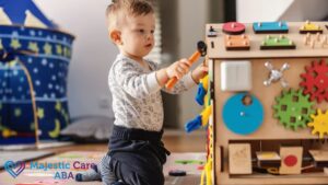 Young boy in a white shirt at an ABA therapy session, confidently stacking blocks with focus.