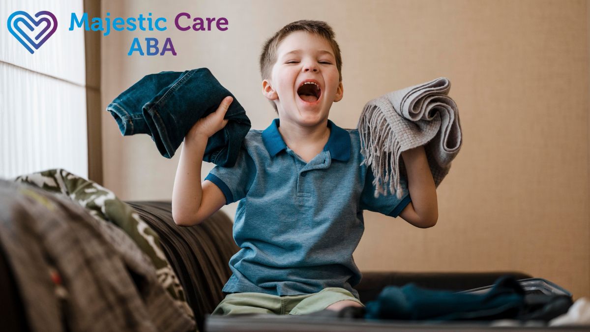 A boy practices autism life skills by organizing his clothes while looking joyfully at the camera.