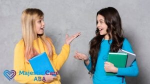Two girls holding books and engaging in animated conversation, illustrating examples of verbal behavior in ABA.