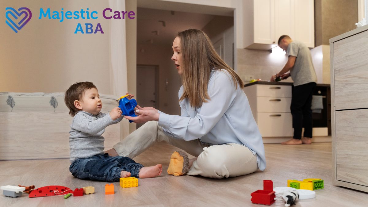 A parent guides her child on the floor surrounded by toys for soothing and sensory play during in-home ABA therapy.
