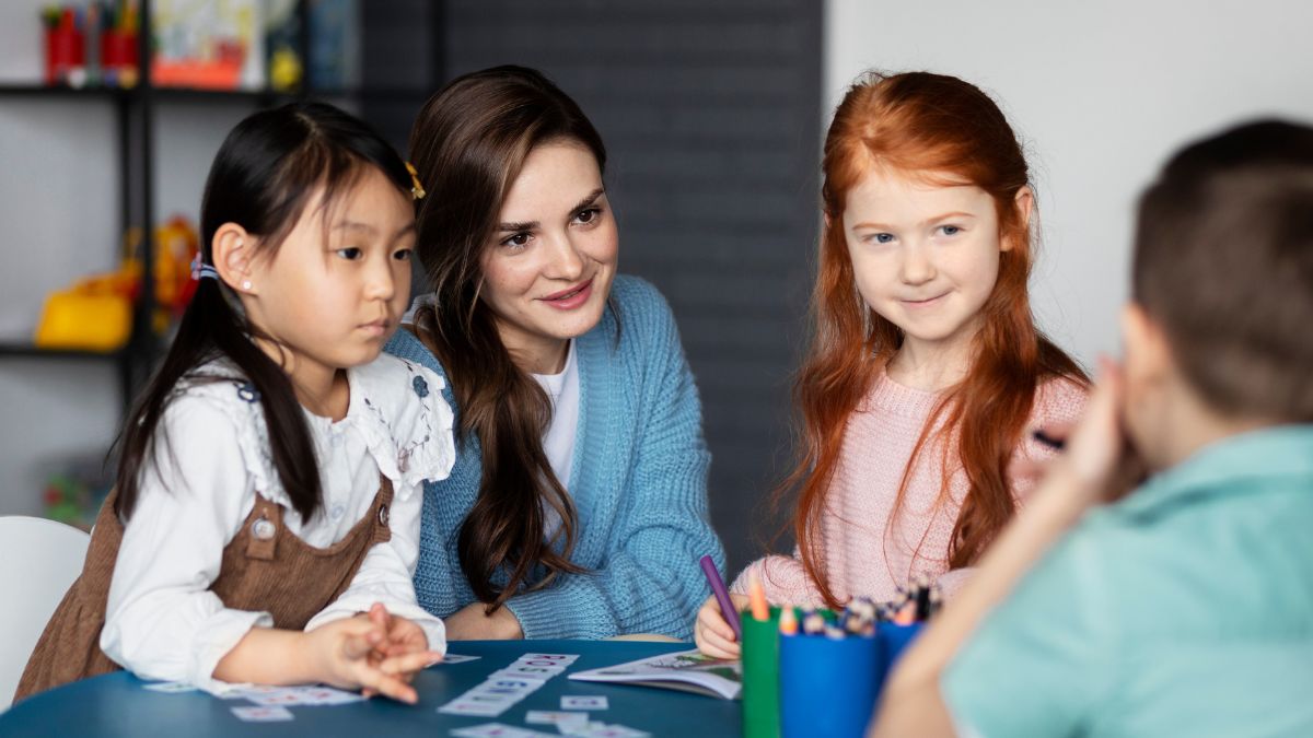 A teacher engages with a group of children in a colorful play therapy room filled with toys and activity tools during an ABA therapy session for kids.
